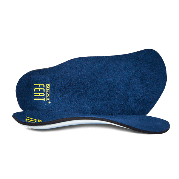 Navy blue Slimline Executive Orthotic insoles with a yellow logo. One insole is standing upright on its side, while the other lies flat on the floor, showcasing their breathable, supportive design.